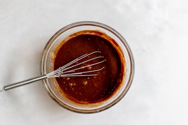 Image, taken from above, shows a glass bowl with a whisk after mixing sugar and egg.