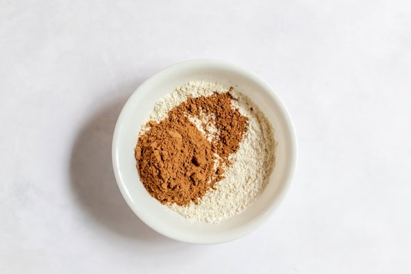 Image, taken from above, shows a white mixing bowl with flours and cocoa