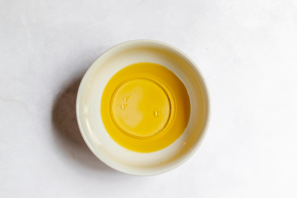 Image shows a small bowl of olive oil photographed from above