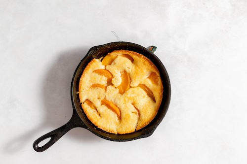 Photo, taken from above, shows an iron skillet with a peach cobbler in it, to be added to the cobbler ice cream.