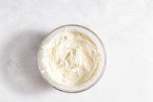 Image, taken from above, shows a glass bowl with the whipped heavy whipping cream in it. 