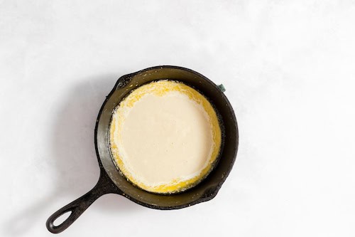 Photo, taken from above, shows an iron skillet with the cobber ice cream ingredients melted.