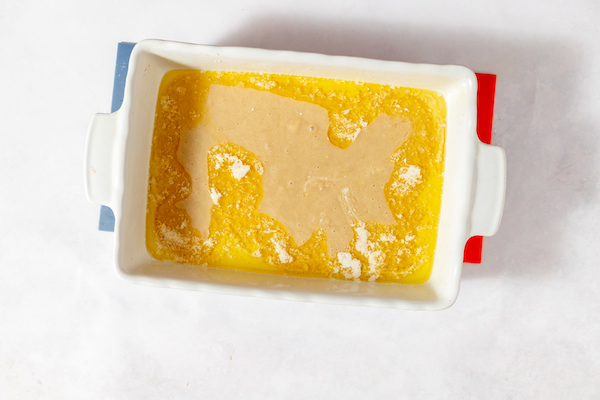 Photo, taken from above, shows the sour cherry cake batter poured into a white pan. 