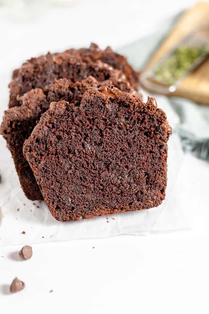 Image shows several slices of gluten free chocolate zucchini bread on a white napkin