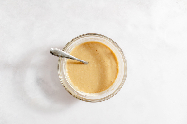 Image, taken from above, shows a glass mixing bowl with mixed batter for sour cherry cake. 