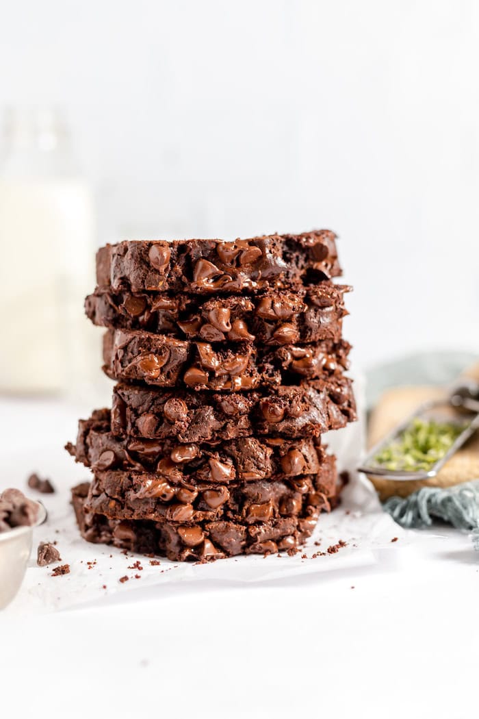 Image shows a stack of sliced chocolate zucchini bread on a white napkin