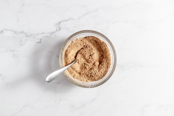 Image shows a glass bowl with a spoon in it with the dry ingredients mixed together