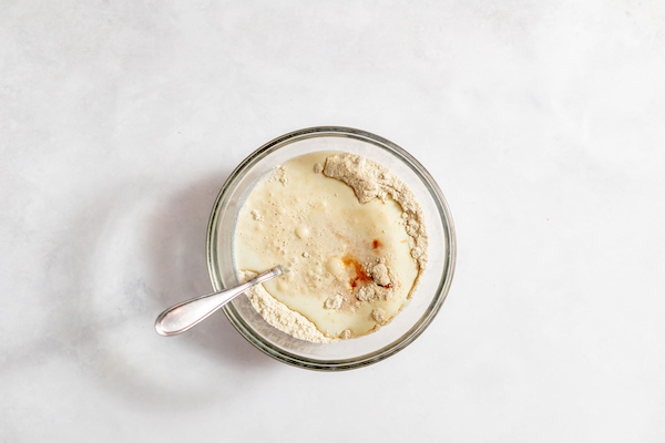 Image shows a glass mixing bowl, photographed from above, full of batter for sour cherry cake.