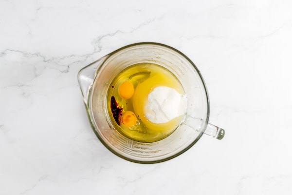 Image show a glass mixing bowl with the wet ingredients for zucchini bread