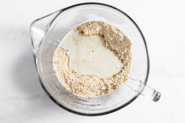 Image, taken from above, shows melted butter poured into a glass mixing bowl full of dry ingredients. 