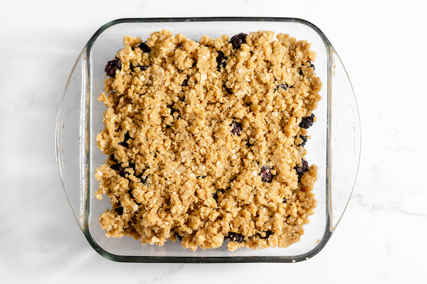 Image, taken from above, shows the crisp mixture poured over the blackberries in the square pan.