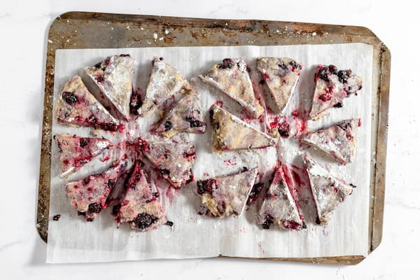 Image, taken from above, shows the dough for blackberry scones on a pan, ready to bake