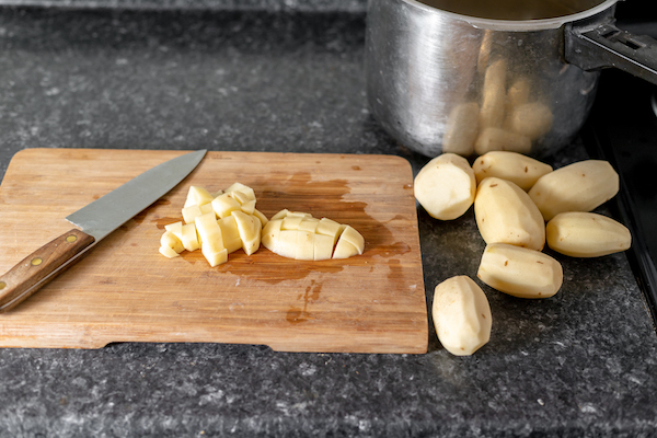 raw potatoes being sliced on a cutting board