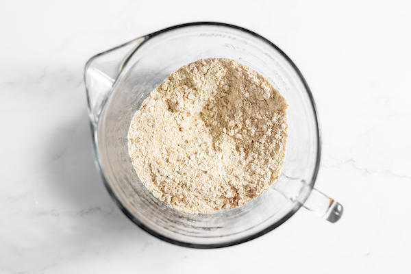 Image, taken from above, shows the dry ingredients for blackberry crisp mixed together in a glass mixing bowl. 