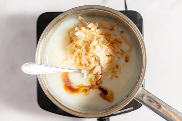 Image, taken from above, shows a pot with the ingredients to make pudding being mixed with the with coconut chips