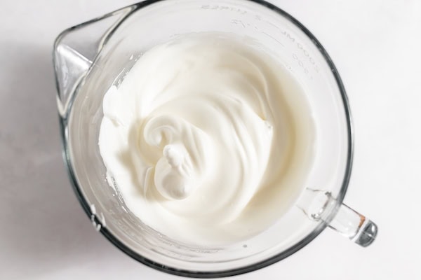 Image, taken from above, shows a glass mixing cup with the meringue for topping pie