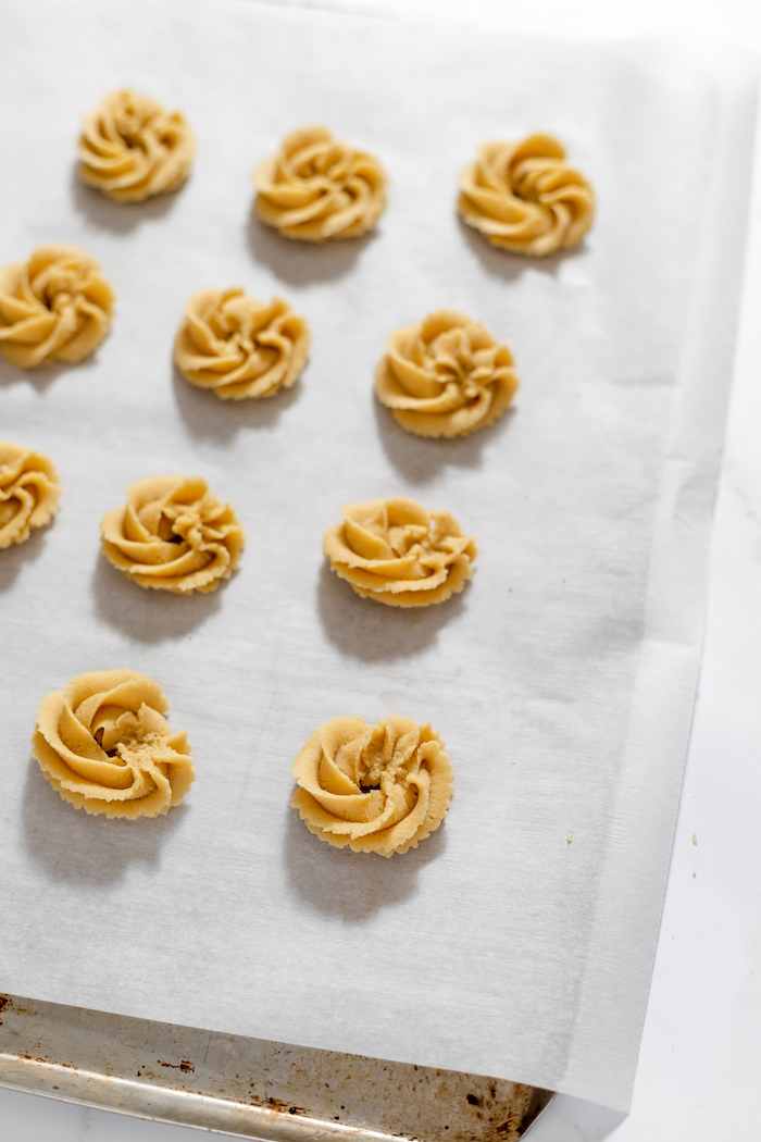 Image shows butter cookie batter on a parchment paper ready to bake
