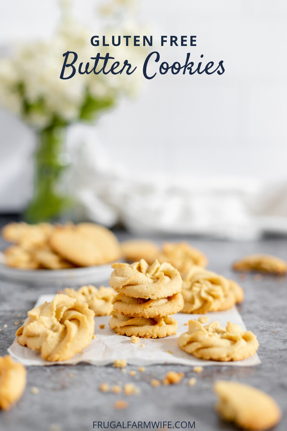 Image shows a piece of parchment paper on a countertop with several gluten free butter cookies stacked on it. Blurred in the background is a plate of cookies. Text overlay reads "Gluten Free Butter Cookies"