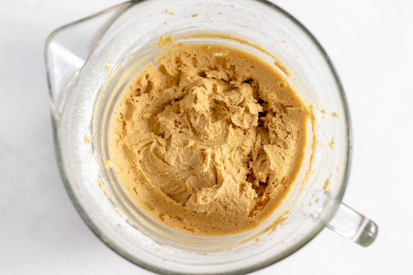 Image shows a glass mixing bowl with batter for gluten free peanut butter cookies