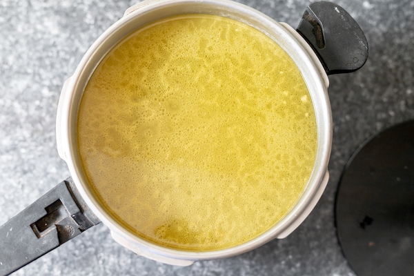 Image, taken from above, shows a pot of strained broth ready to ladle into jars.