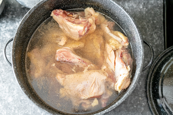Photo shows a stock pot, photographed from above, full of chicken cooking