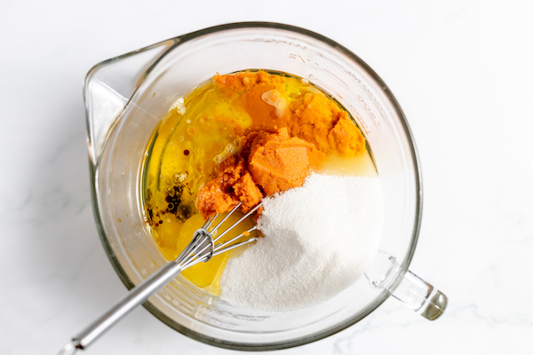 Image, taken from above, shows the eggs, oil, pumpkin puree ready to be whisked together to make gluten free pumpkin muffins