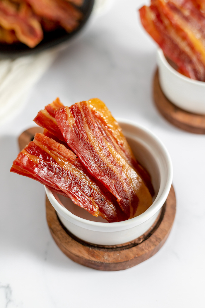 Image shows several small white ramekins on a counter holding jerky made from bacon