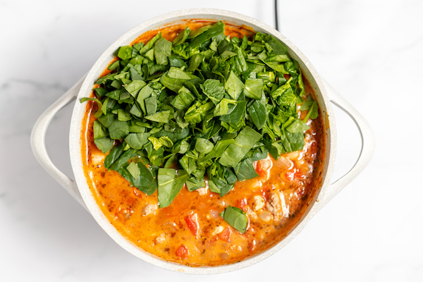 adding spinach to peasant soup