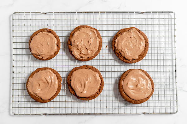 Photo shows hot chocolate cookies on a cooling rack, photographed from above, with mouse on each cookie. 