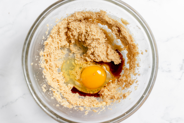 Image, taken from above, shows a glass bowl with egg, vanilla added to the rest of the ingredients mixed together. 
