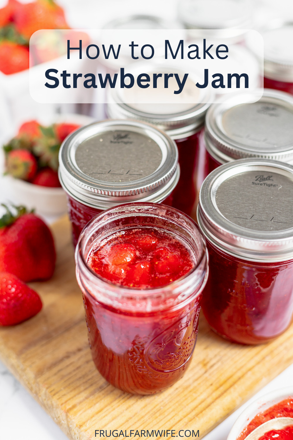 Image shows several mason jars of strawberry jam sitting on a wooden cutting board. The front jar is open, revealing the jam, and several fresh strawberries sit nearby on the board. Text above reads "How to Make Strawberry Jam"