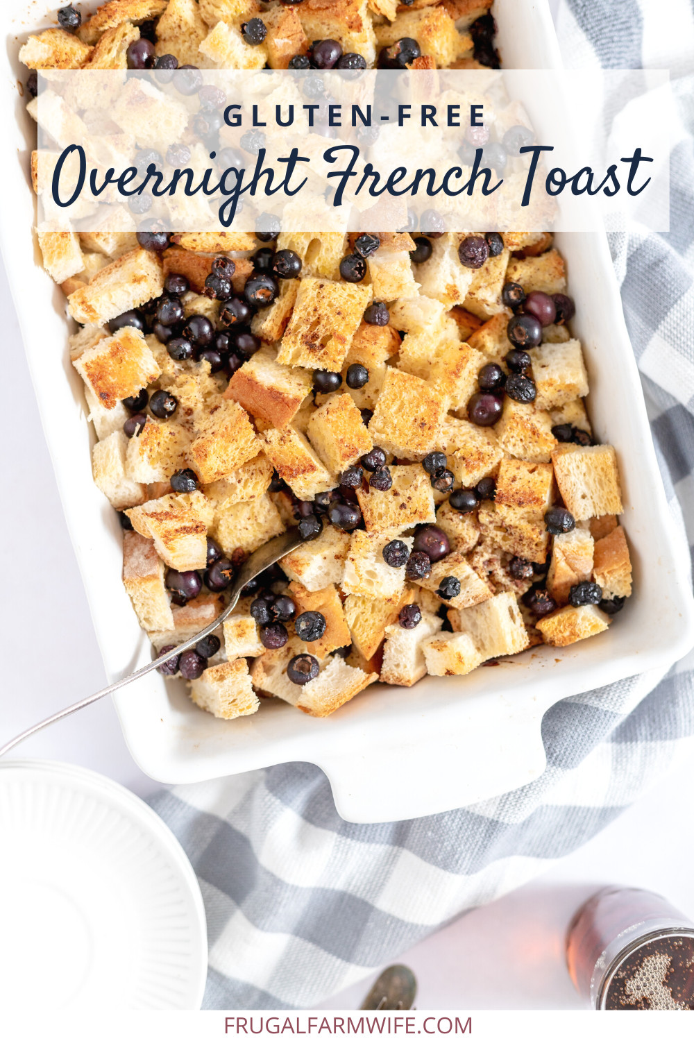 Image, taken from above, shows a pan of gluten free overnight French toast, with chunks of bread and blueberries sprinkled. Text overlay reads "Gluten Free Overnight French Toast"