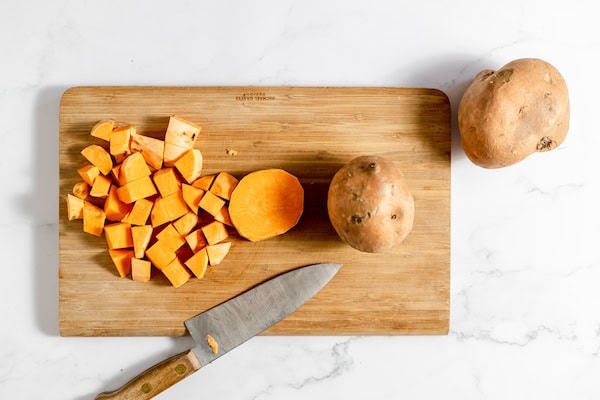 cubing sweet potatoes on a cutting board