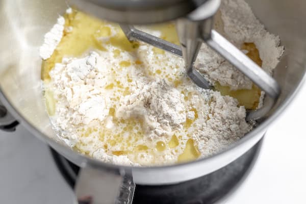 Image, taken from above, shows a mixer which is combining milk, water, yeast, and flour