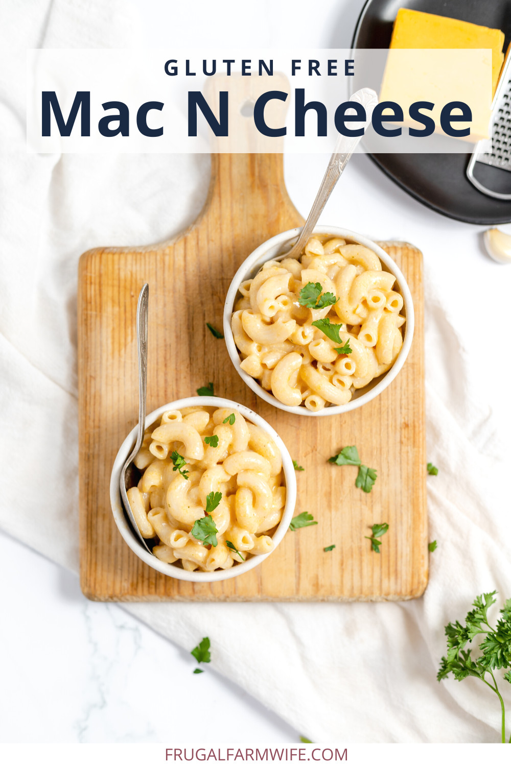 Image, taken from above, shows two bowls of gluten free mac n cheese served on a cutting board. Text overlay reads "Gluten Free Mac N Cheese"