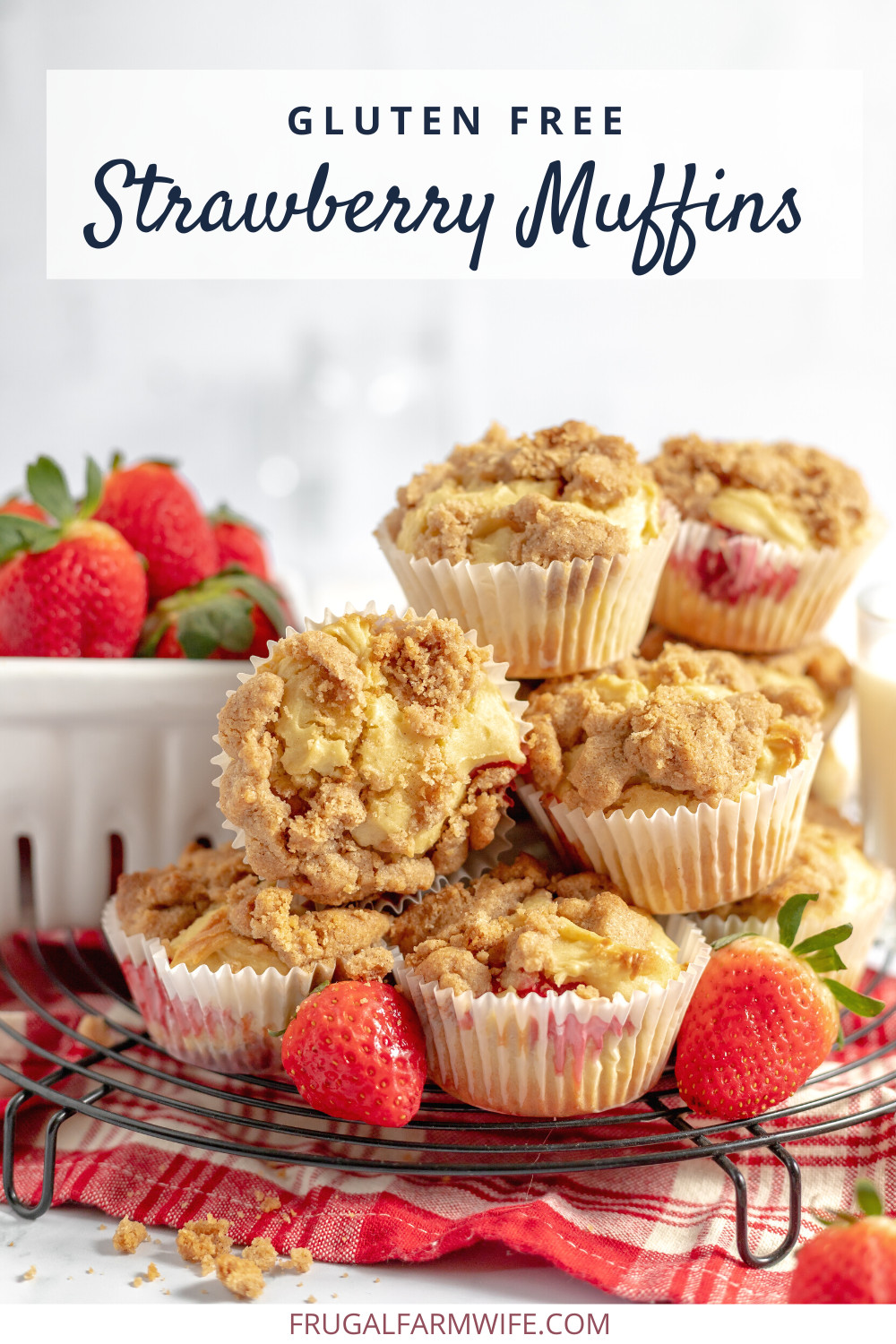 Image shows a stack of gluten free strawberry muffins on a wire cooling rack. A few strawberries sit on the rack next to the muffins, and a large white bowl of more strawberries sits behind the stack. Text above reads "Gluten Free Strawberry Muffins"
