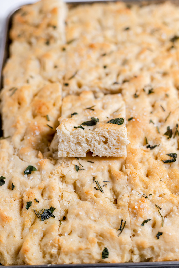 Image shows a close up of sliced gluten free focaccia in a pan