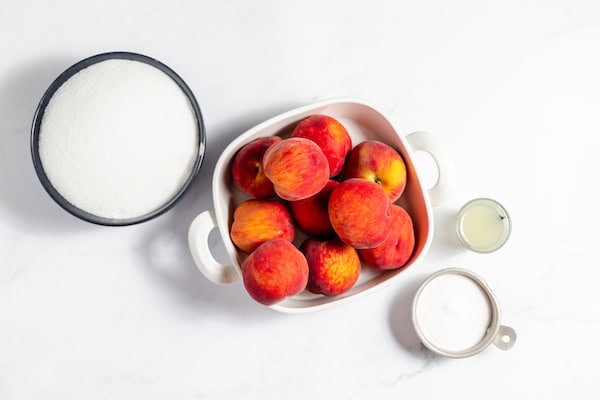 Image, taken from above, shows the ingredients needed for making peach jam laid out on a table