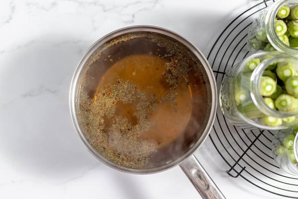 hot pickling brine next to jars full of okra