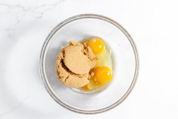 Image, taken from above, shows brown sugar and eggs in a bowl