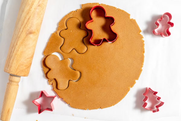 Image, taken from above, shows gluten free ginger cookies dough rolled out with cookie cutters in it