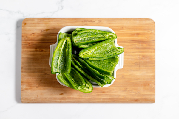 Image, taken from above, shows a small dish of deseeded peppers ready to purée on a cutting board. 