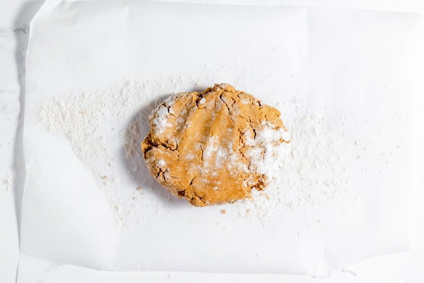 Image, taken from above, shows chilled gingerbread cookie dough on a large piece of parchment paper, ready to be rolled out