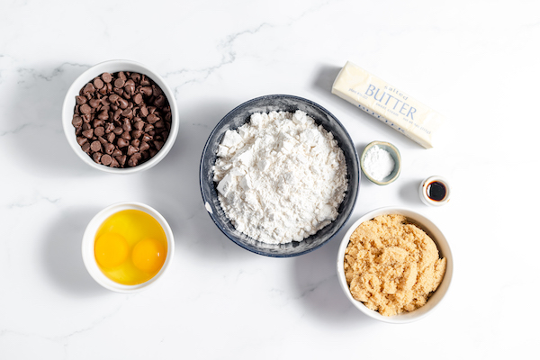 Image, taken from above, shows bowls of ingredients for making gluten free blondies laid out on a counter top