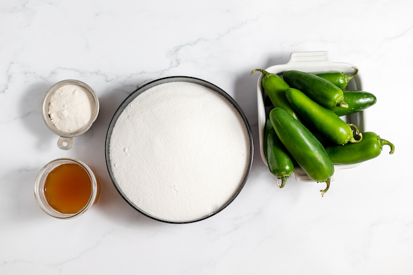 Image, taken from above, shows the ingredients for making homemade jalapeño jelly laid out on a counter.