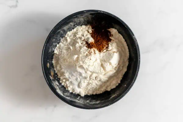 Image, taken from above, shows a black mixing bowl with the dry ingredients in it to make espresso toffee cookies.