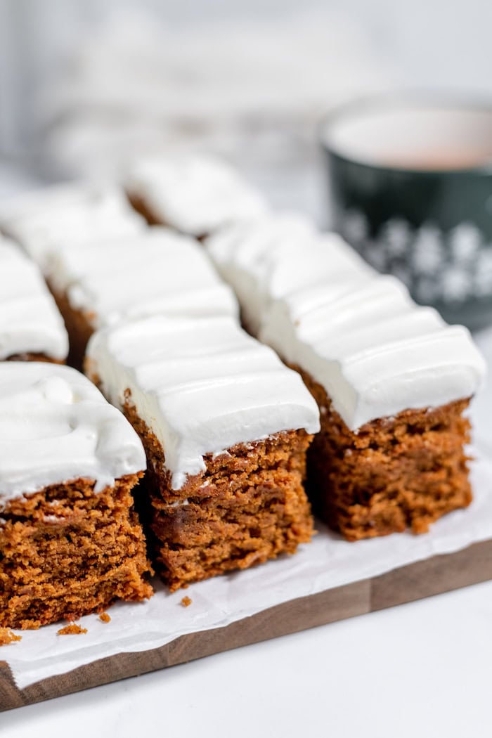 a serving platter with gluten free gingerbread bars topped with whipped cream