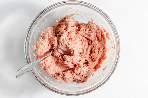 Image, taken from above shows a glass bowl with the meatball's turkey mixture blended together.