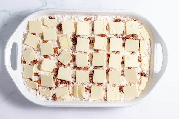 butter arranged over dump cake ingredients in a baking pan