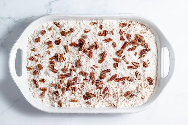 pecans sprinkled over cake mix in a pan